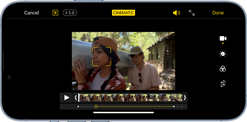 The Edit screen of a Cinematic mode video in landscape orientation. At the top left of the screen is the Cancel button, the Cinematic Manual button, and the Depth Adjustment button. At the top center of the screen, the Cinematic button is selected. At the top right of the screen is the Volume button, the Enter Full Screen button, and the Done button. The video is in the center of the screen and there is a frame around the focus subject. Below the video is the frame viewer that displays the point in the video where the subject focus changes. The editing tools are on the right side of the screen, from the top to bottom: Video, Adjust Color, Filter, and Crop.