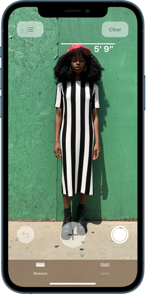 A person’s height is measured, with the height measurement showing at the top of the person’s head. The Take Picture button is active near the lower-right corner for taking a picture of the measurement. The green Camera In Use indicator appears at the top right.