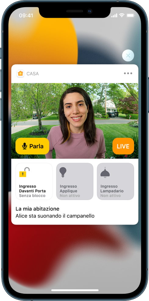 Sullo schermo di iPhone si trova una notifica di Casa. Mostra la foto di una persona davanti alla porta d'ingresso con un pulsante Parla a sinistra. Sotto, si trovano pulsanti secondari per l'illuminazione dell'area antistante la porta e dell'ingresso. Compare la frase “Alice sta suonando il campanello”. In alto a destra della notifica è presente un pulsante Chiudi.