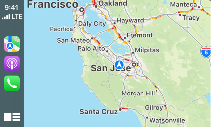 „CarPlay“ kairėje rodomos „Maps“, „Podcasts“ ir „Settings“ piktogramos, o dešinėje – dabartinės vietovės žemėlapis