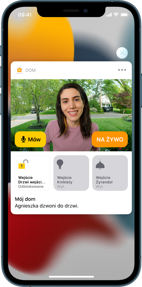 Powiadomienie z aplikacji Dom na ekranie iPhone’a. Zawiera ono zdjęcie osoby stojącej za drzwiami wejściowymi. Po lewej widoczny jest przycisk Mów. Poniżej znajdują się przyciski akcesoriów: drzwi wejściowych oraz świateł. Widoczny jest napis „Agnieszka dzwoni do drzwi”. W prawym górnym rogu powiadomienia znajduje się przycisk Zamknij.
