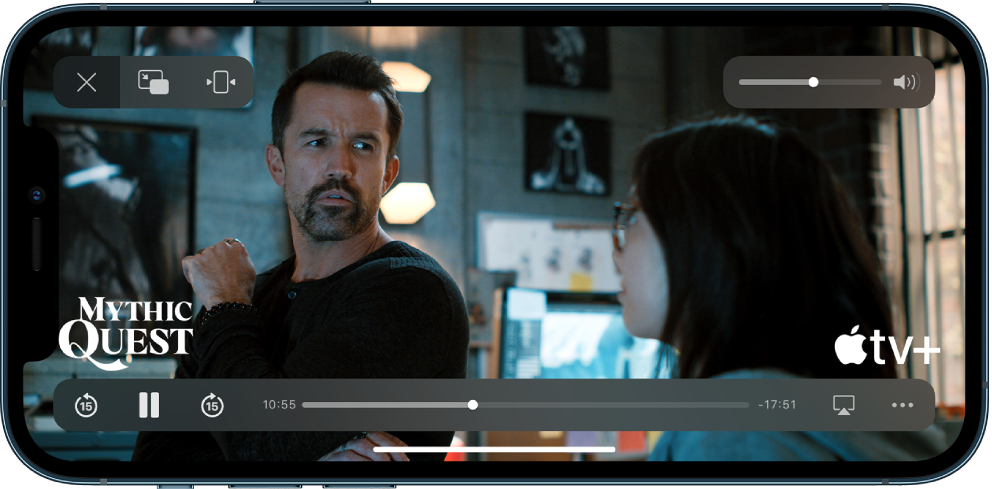 Filme sendo reproduzido, com os controles aparecendo. Os botões Fechar, PIP e Zoom estão na parte superior esquerda. O controle deslizante de volume está na parte superior direita. Na parte inferior esquerda, os botões para retroceder 15 segundos, pausar e avançar 15 segundos. Ao longo da parte inferior central, um controle deslizante que pode ser arrastado para ajustar a posição do vídeo; o tempo decorrido e o tempo remanescente aparecem em cada um dos lados do controle deslizante. Na parte inferior direita, há botões para alterar o destino do vídeo e mostrar mais controles.