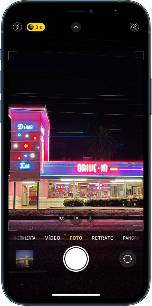 Tela da Câmera no modo Foto. Botões do flash e do modo Noite aparecem no canto superior esquerdo da tela. O flash está desativado e o modo Noite está ativado. O botão Controles da Câmera está na parte superior central e o botão Live Photo está no canto superior direito. Na parte inferior da tela estão, da esquerda para a direita, o botão Visualizador de Foto e Vídeo, o botão Tirar Foto e o botão Seletor de Câmera Traseira.