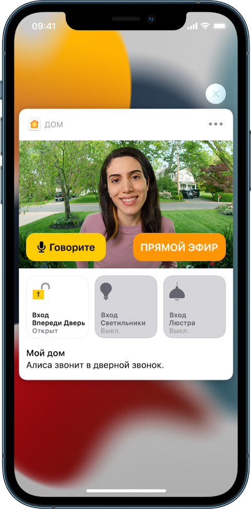 Уведомление из приложения «Дом» отображается на экране iPhone. На нем изображен человек у входной двери и кнопка «Говорите» слева. Ниже расположены кнопки аксессуаров для управления входной дверью и освещением при входе. Слова «Саша звонит в дверь». Кнопка «Закрыть» находится в правом верхнем углу уведомления.