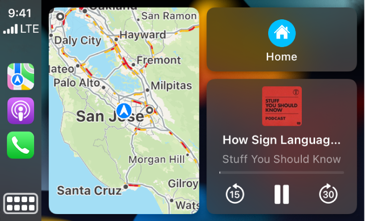 CarPlay Dashboard që shfaq ikonat për Maps, Podcasts dhe Phone në të majtë, hartën e itinerarit të drejtimit në mes, dhe tre artikuj të stivosur në të djathtë. Artikulli në krye në të djathtë tregon navigimin për te Gas Stations dhe Parking. Artikulli në mes në të djathtë tregon kontrollet e luajtjes së medias. Artikulli më poshtë tregon një takim të ardhshëm të kalendarit.