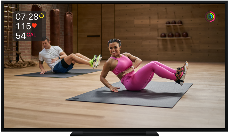 Una TV mostrando un entrenamiento de core de Apple Fitness+ con mediciones en la pantalla, que incluyen el tiempo restante, frecuencia cardiaca y calorías quemadas.