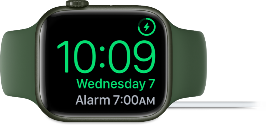 Apple Watch가 옆으로 누워있고 충전기에 연결되어 있음. 화면의 오른쪽 상단 모서리에는 충전 기호가 있고 그 아래에는 현재 시간과 다음 알람 시간이 있음.