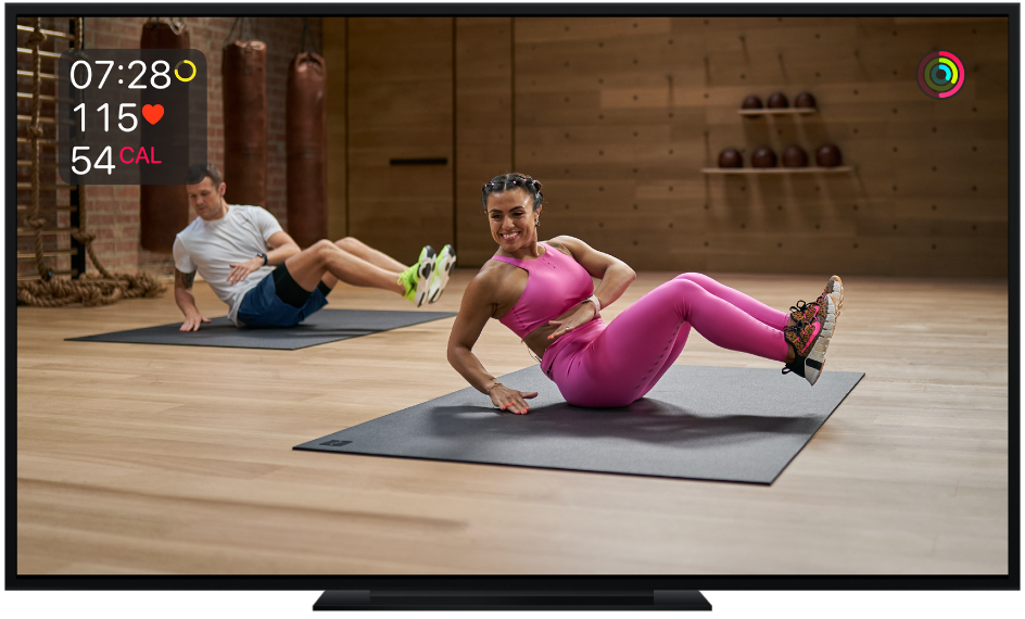 Телевизор, показващ основна тренировка в Apple Fitness+ с показани на екрана данни за оставащо време, сърдечен ритъм и калории.