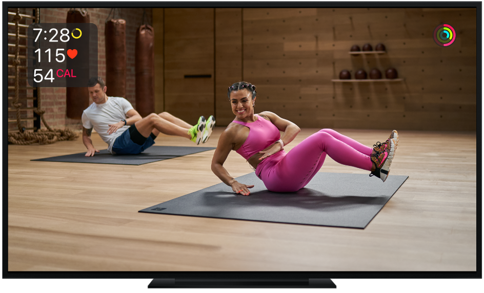 Un televisor mostra un entrenament de tronc de l’Apple Fitness+. A la pantalla hi apareix el temps restant i els mesuraments de freqüència cardíaca i calories.