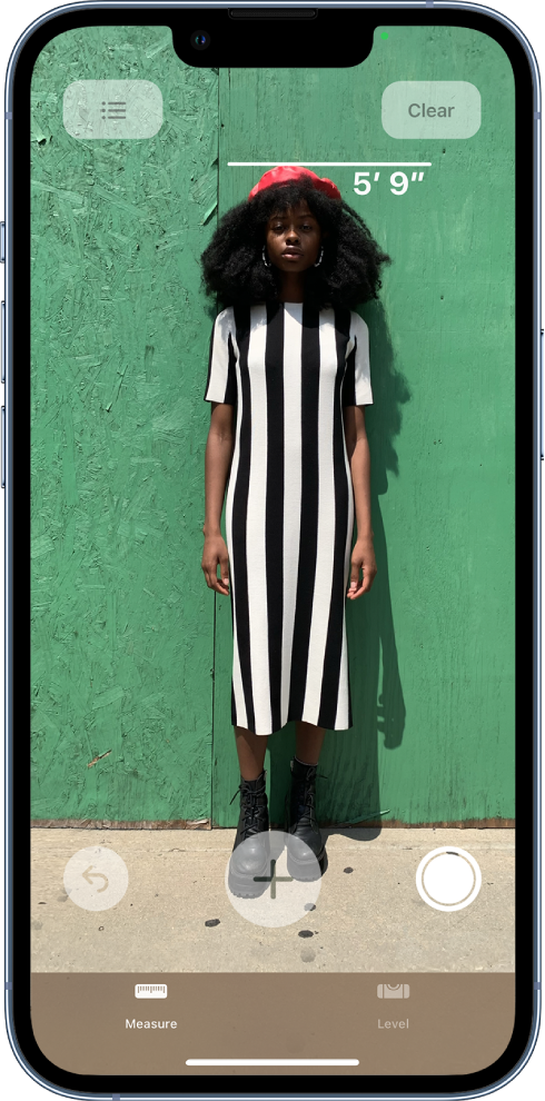 A person’s height is measured, with the height measurement showing at the top of the person’s head. The Take Picture button is active near the lower-right corner for taking a picture of the measurement. The green Camera In Use indicator appears at the top right.