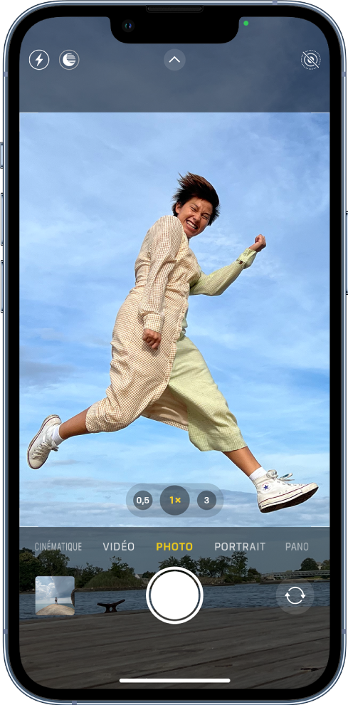 L’écran Appareil photo en mode Photo, avec les autres modes à gauche et à droite sous le viseur. Les boutons pour le flash, le mode Nuit, les commandes de l’appareil photo, le format ProRaw et le mode Live&nbsp;Photo apparaissent en haut de l’écran. En dessous des différents modes d’appareil photo, de gauche à droite, se trouvent le bouton «&nbsp;Visualiseur de photos et vidéos&nbsp;», le bouton «&nbsp;Prendre une photo&nbsp;» et le bouton «&nbsp;Sélecteur de caméra - face arrière&nbsp;».