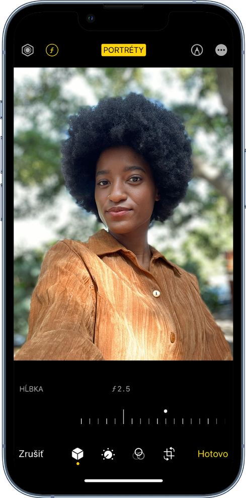 Obrazovka úprav pre fotku nasnímanú v režime Portrét. V ľavej hornej časti obrazovky sa nachádza tlačidlo na nastavenie intenzity osvetlenia a tlačidlo na nastavenie hĺbky. Hore uprostred sa nachádza tlačidlo Portrét, ktoré je aktivované, a vpravo hore je tlačidlo doplnkov. Fotka sa nachádza v strede obrazovky a pod ňou je posuvník na úpravu nastavenia hĺbky. Pod posuvníkom sa zľava doprava nachádzajú tlačidlá Zrušiť, Portrét, Upraviť, Filtre, Orezať a Hotovo.