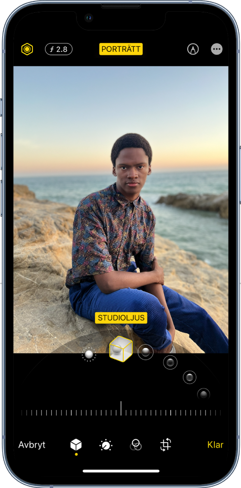 Skärmen Ändra med en bild i porträttläge. Högst upp till vänster på skärmen sitter ljusintensitetsknappen och djupkontrollknappen. Högst upp i mitten på skärmen är porträttknappen på och högst upp till höger finns knappen Märk. Bilden visas på mitten av skärmen och under bilden finns ett reglage för att välja porträttljuseffekten. Under det finns ett reglage för att justera värdet. Från vänster till höger längst ned på skärmen finns knapparna Avbryt, Porträtt, Justera, Filter, Beskär och Klar.