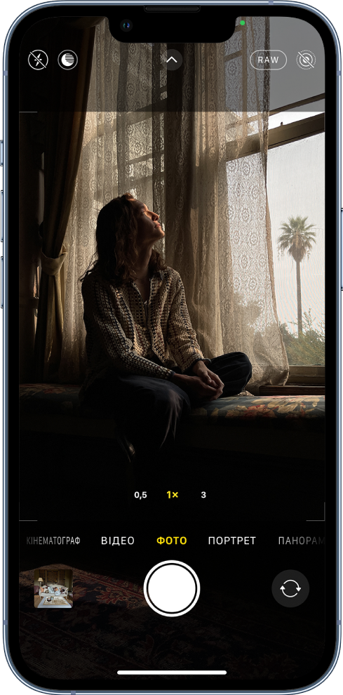 Екран Камери в режимі «Фото». Кнопки для спалаху та режиму «Ніч» відображаються в лівому верхньому куті екрана. Кнопку «Спалах» і кнопку нічного режиму вимкнено. Кнопка «Елементи керування камери» розташована вгорі по центру, а кнопка ProRAW і кнопка Live Photo — у верхньому правому куті. Кнопку ProRAW ввімкнено, а кнопку Live Photo вимкнено. У нижній частині екрана зліва направо розташовані кнопки «Програма перегляду фото та відео», «Зробити знімок» і «Вибір задньої камери».