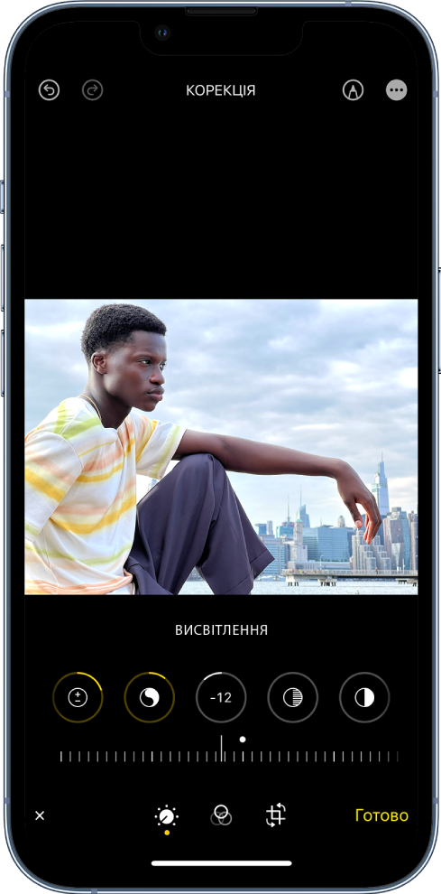 Екран «Редагувати» з фотографією в центрі. Під фотографією розташовані кнопки редагування для ефектів «Корекції», «Експозиція», «Освітленість» і «Висвітлення». Вибрано кнопку «Яскравість». Під кнопками для редагування є повзунок, який дає змогу налаштувати рівні яскравості. Під повзунком зліва направо розташовані кнопки «Налаштувати», «Фільтри», «Обрізати» та «Готово». Кнопка «Розмітка» розташована у верхньому правому куті.