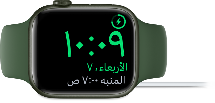 Apple Watch موضوعة على جانبها ومتصلة بالشاحن، وتعرض الشاشة رمز الشحن في الزاوية العلوية اليمنى، والوقت الحالي أسفل ذلك، ووقت المنبه التالي.