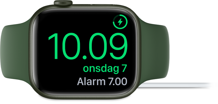 Et Apple Watch, der ligger på siden og er sluttet til opladeren, hvor skærmen viser opladersymbolet øverst til højre, det aktuelle klokkeslæt derunder og klokkeslættet for den næste alarm.