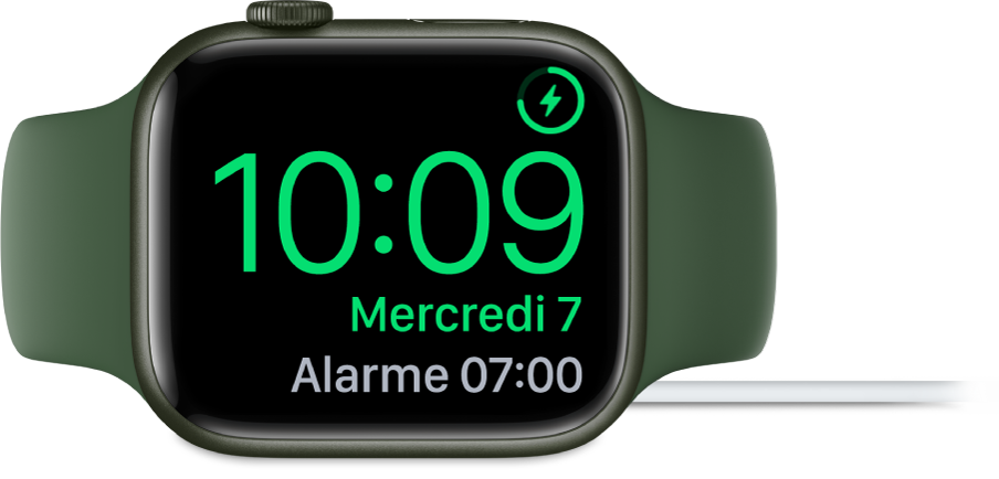 Apple Watch placée sur le côté et connectée au chargeur, dont l’écran affiche le symbole de charge en haut à droite, l’heure actuelle en dessous et l’heure de la prochaine alarme.