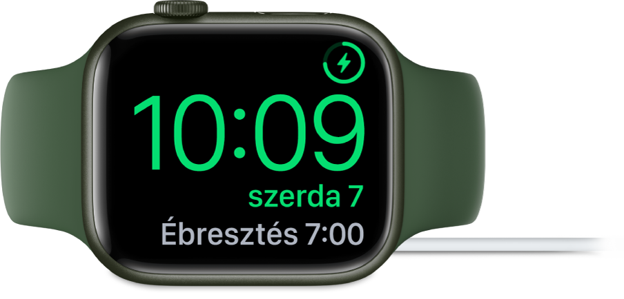 Oldalára fektetett és töltőre csatlakoztatott Apple Watch; a számlap jobb felső sarkában látható a töltés jele, alatta az aktuális idő és a következő jelzés ideje.