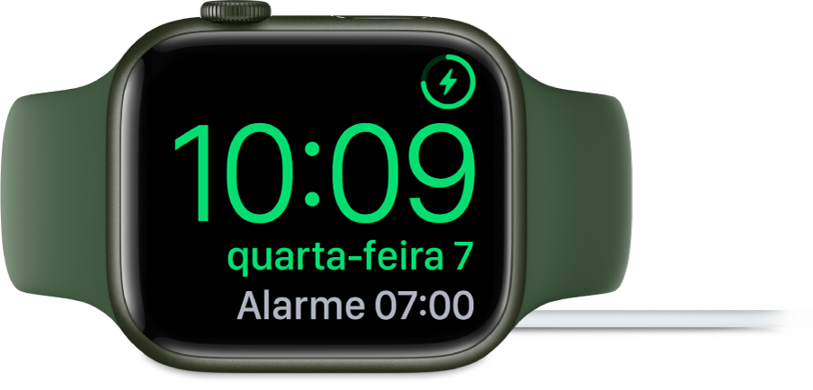 Um Apple Watch colocado de lado e ligado ao carregador, com o ecrã, com o símbolo de carregamento no canto superior direito e, por baixo, a hora atual e a hora do próximo alarme.