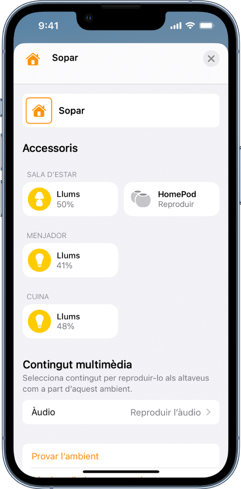 Pantalla d’edició d’un ambient a l’app Casa. El nom de l’ambient es troba a la part superior de la pantalla. A sota, hi ha tres habitacions i els accessoris que s’han afegit a cada habitació com a part d’un ambient. A prop de la part inferior de la pantalla, hi ha la secció “Contingut multimèdia” on s’ha configurat un HomePod a la sala d’estar per reproduir àudio. A la part inferior de la pantalla hi ha el botó “Provar l’ambient”.