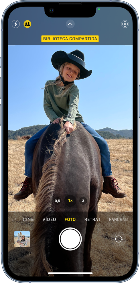 La pantalla de l’app Càmera està oberta i un tema ocupa el marc. A la part superior de la pantalla de l’app Càmera, el botó “Fototeca compartida” està activat.