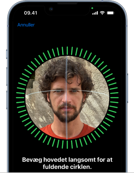 Skærmen til indstilling af genkendelse med Face ID. Der vises et ansigt omsluttet af en cirkel på skærmen. Teksten under ansigtet instruerer brugeren i at bevæge hovedet langsomt for at gøre cirklen færdig.