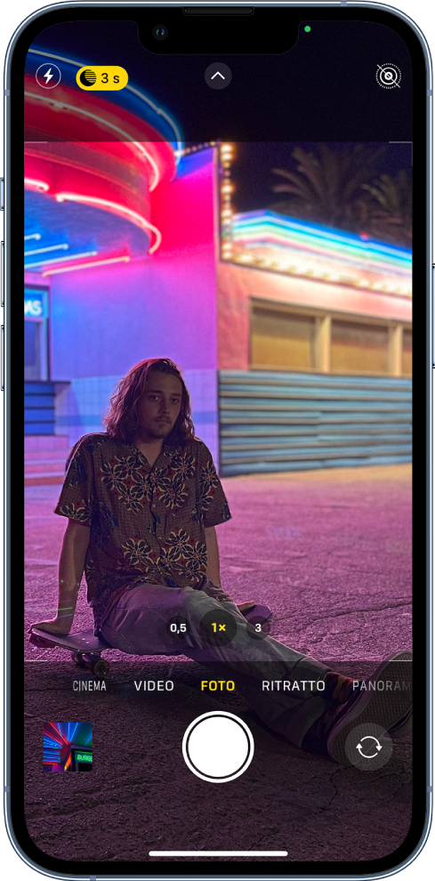 Una schermata di Fotocamera in modalità Foto. I pulsanti per il flash e per la modalità notturna sono visibili nell'angolo in alto a sinistra dello schermo. Il flash viene disattivato e viene attivata la modalità notturna. Il pulsante di controlli della fotocamera si trova in alto al centro e il pulsante Live Photo si trova nell'angolo in alto a destra. Nella parte inferiore dello schermo sono visibili, da sinistra a destra, il pulsante per visualizzare le foto e i video, il pulsante di scatto e il selettore per la fotocamera posteriore.