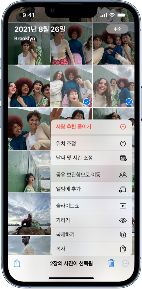 사진 축소판 격자가 화면을 채우고 있음. 축소판 중 두 개가 선택되어 있고 화면 하단에 더 보기 메뉴가 열려 있음. 메뉴에서 ‘공유 보관함으로 이동’ 옵션이 선택되어 있음.