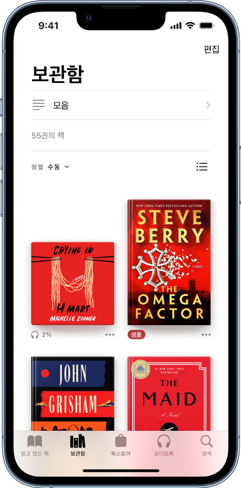 도서 앱의 보관함 화면. 화면 상단에는 모음 버튼과 정렬 옵션이 있음. 수동 정렬 옵션이 선택됨. 화면 중간에는 보관함에 있는 책 표지가 나타남. 화면 하단 왼쪽부터 오른쪽으로 읽고 있는 책, 보관함, 북스토어, 오디오북 및 검색 탭이 있음.