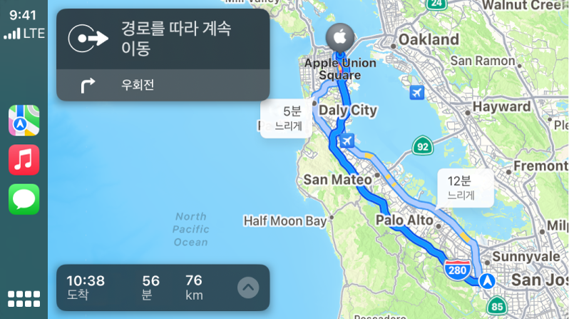 왼쪽에는 지도, 음악 및 메시지 아이콘, 오른쪽에는 회전 방향 및 예상 도착 정보가 있는 운전 경로 지도를 표시하는 CarPlay.