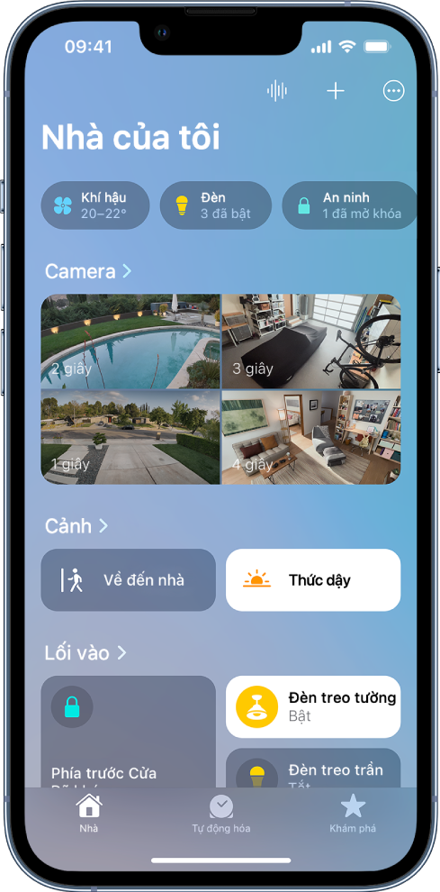 Tab Nhà với các danh mục ở đầu màn hình. Các hình ảnh từ bốn camera an ninh xuất hiện bên dưới đề mục Camera. Các hình ảnh hiển thị một sân sau, gara, sân trước và phòng khách. Hai cảnh xuất hiện ở giữa màn hình, với một phòng và các phụ kiện của phòng xuất hiện ở bên dưới.