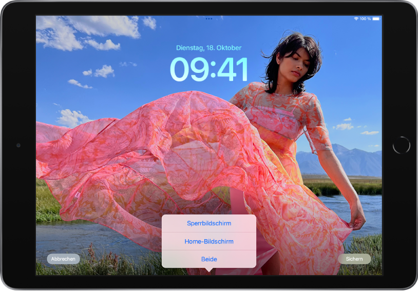 Der iPad-Sperrbildschirm, der mit einem mit einem Benutzer:innenfoto ausgefüllt ist. Oben auf dem Bildschirm befinden sich die Steuerelemente zum Festlegen des Fotos für den Sperrbildschirm (von links nach rechts): die Taste „Abbrechen“, das Menü mit den Optionen „Sperrbildschirm“, „Home-Bildschirm“ und „Beide“ sowie die Taste „Festlegen“.