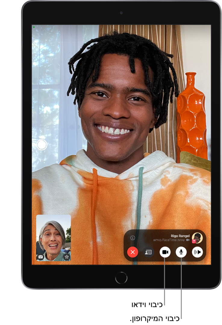 רואים שיחת FaceTime במהלך התרחשותה. התמונה שלך מופיעה בתוך אריח קטן בקרבת הפינה השמאלית התחתונה, והתמונה של האדם השני ממלאת את שאר המסך. האריח הקטן כולל את הכפתורים ״אפקטים״ ו״עבור למצלמה אחורית״. הכפתור Live Photo מופיע בצדו הימני של המסך. הפקדים של FaceTime מופיעים בתחתית המסך, כולל הכפתורים ״שמע״, ״מיקרופון״, ״מצלמה״, ״שיתוף תוכן״ ו״סיום״. מעל הפקדים נמצאים שם או Apple ID של האדם עמו מבוצעת השיחה והכפתור ״מידע״.
