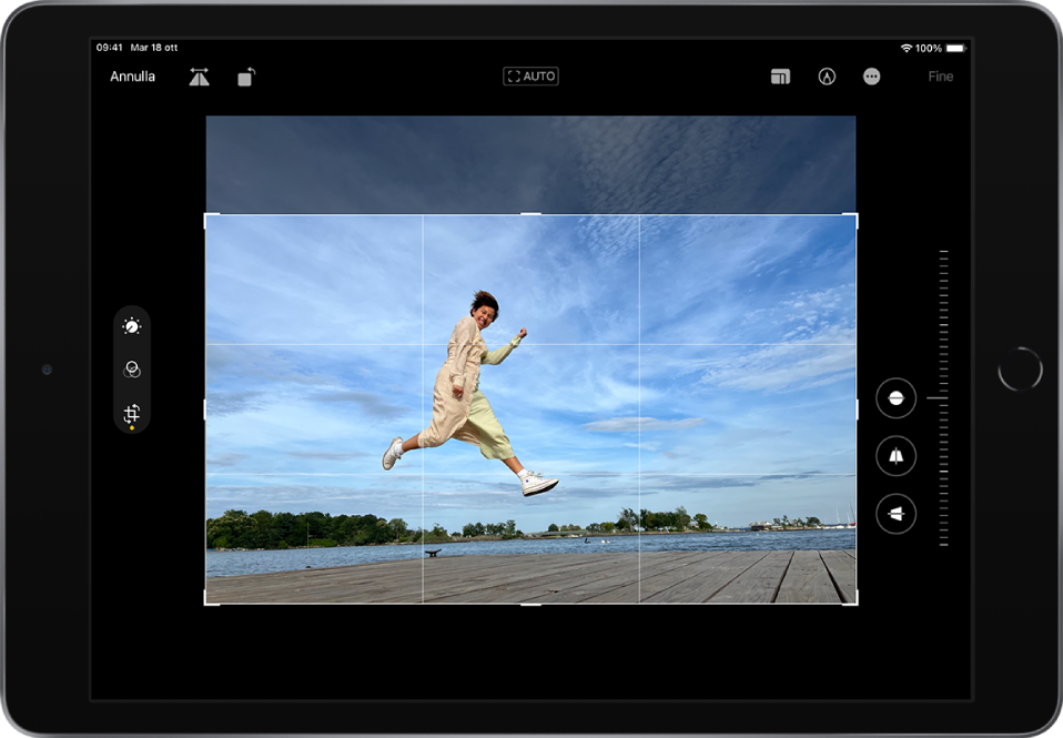 iPad in orientamento orizzontale. Al centro dello schermo è visibile una foto in modalità di modifica con una griglia in sovrapposizione e un riquadro per il ritaglio. Sul lato sinistro dello schermo sono presenti i pulsanti Regola, Filtri e Ritaglia; il pulsante Ritagliai è selezionato. Sul lato destro dello schermo sono visibili le opzioni per la regolazione del ritaglio e il cursore per l'intensità. Nell'angolo superiore sinistro sono presenti i pulsanti Annulla, Capovolgi e Ruota. Nell'angolo superiore destro sono presenti i pulsanti Proporzioni, Modifica e Fine.