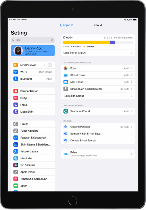 Skrin Seting dengan nama pengguna dipilih di bahagian atas bar sisi di sebelah kiri skrin. Di sebelah kanan skrin ialah pilihan untuk seting iCloud termasuk meter storan iCloud, serta senarai app dan ciri, termasuk Foto, iCloud Drive, iCloud Mail, serta Kata Laluan dan Rantai Kunci.