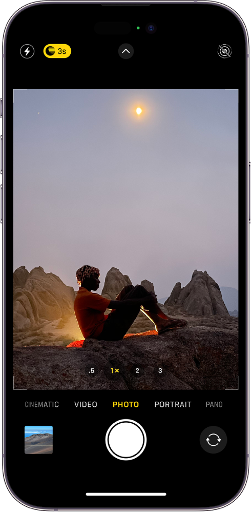 The Camera screen in Photo mode. Within the viewfinder is a night scene. Buttons for flash and Night mode appear in the top-left corner of the screen and Night mode is on. The Camera Controls button is in top center, and the Live Photos button is in the top-right corner. At the bottom of the screen are, from left to right, the Photo and Video Viewer button, the Take Picture button, and the Camera Chooser Back-Facing button.