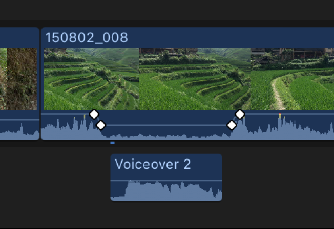 A video clip in the timeline showing keyframes on either side of a section of lowered volume, giving prominence to a voiceover audio clip connected below