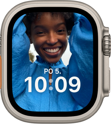 Ciferník Portréty s fotkou ze synchronizovaného fotoalba. V dolní třetině obrazovky je vidět datum a čas.