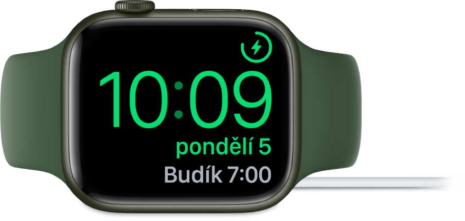 Hodinky Apple Watch položené na boku a připojené k nabíječce; na obrazovce se v pravém horním rohu ukazuje symbol nabíjení, pod ním aktuální čas a nejbližší nastavený čas buzení.