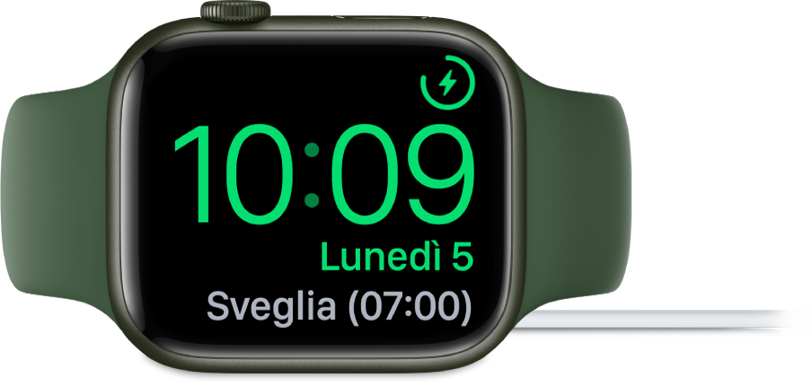 Apple Watch appoggiato su un lato e collegato al caricabatterie, con lo schermo che mostra il simbolo di ricarica nell’angolo superiore destro, l’ora attuale sotto e l’orario della prossima sveglia.