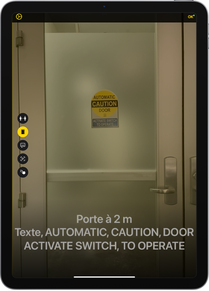 L’écran Loupe en mode de détection affichant une porte. Une description précisant le texte figurant sur la porte ainsi que la distance qui la sépare de l’utilisateur s’affiche en bas de l’écran.