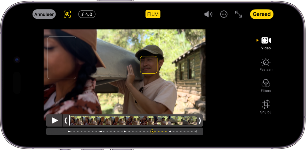 Het bewerkingsscherm van een film in liggende weergave. Linksboven in het scherm staan de annuleerknop, de knop voor de handmatige filmmodus en de knop voor de diepteaanpassing. Boven in het scherm is de knop 'Film' geselecteerd. Rechtsboven in het scherm staan de volumeknop, de knop voor meer opties, de knop voor de schermvullende weergave en de knop 'Gereed'. De video staat in het midden van het scherm en er staat een kader rond het focusonderwerp. Onder de video staat de frameviewer met het punt in de video waar de focus naar een ander onderwerp wordt verplaatst. Aan de rechterkant van het scherm staan de bewerkingsknoppen, met van boven naar beneden: 'Video', 'Pas aan', 'Filters' en 'Snij bij'.