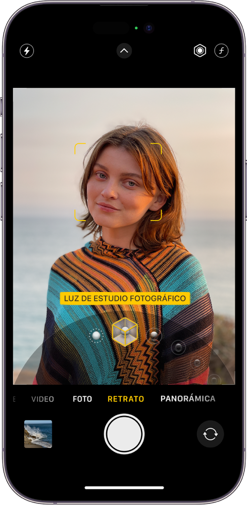 La pantalla de la app Cámara el modo Retrato; en el visor, el objeto se muestra nítido y el fondo difuminado. El dial para seleccionar la iluminación de retrato está abierto debajo del visor, y el efecto Luz de estudio fotográfico está seleccionado. En la parte superior izquierda de la pantalla se encuentra el botón Flash; en la superior central, el botón Controles de cámara; y, en la superior derecha, los botones para ajustar la intensidad de la iluminación de retrato y el control de profundidad. En la parte inferior de la pantalla, de izquierda a derecha, se encuentran los botones Visor de fotos y videos, Tomar foto y Selector de cámara posterior.
