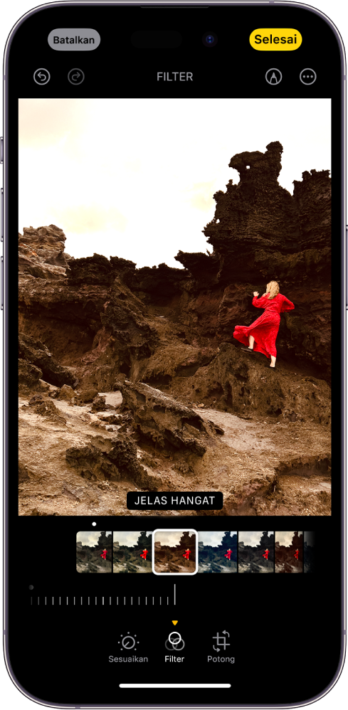 Layar Edit dengan foto di tengah. Di bagian bawah layar, dari kiri ke kanan, terdapat tombol Sesuaikan, Filter, dan Potong. Tombol Filter dipilih dan terdapat penggeser untuk menyesuaikan intensitas filter. Tombol Batalkan terdapat di pojok kiri atas layar dan tombol Selesai terdapat di pojok kanan atas layar. Juga di bagian atas layar, dari kiri ke kanan, terdapat tombol Urungkan, Ulangi, Filter, Markah, dan Plug-in.