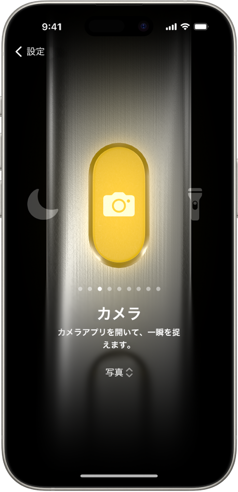 アクションボタンのカスタマイズ画面。現在は「カメラ」がアクションとして選択されています。カメラの左右に、「おやすみモード」や「フラッシュライト」など、ほかの機能が表示されています。アクションの下にあるドットをタップすると、別のアクションに切り替えることができます。選択したアクション「カメラ」の下にはカメラのオプションメニューがあり、タップしてアクションボタンにオプションを割り当てることができます。