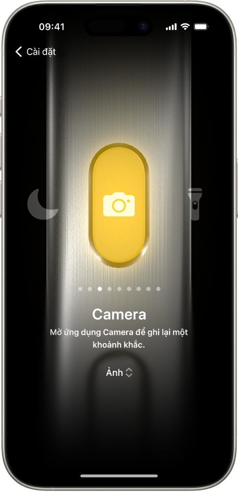 Màn hình để tùy chỉnh nút Tác vụ. Camera là tác vụ được chọn. Các tính năng khác xuất hiện ở bên phải và bên trái của camera, bao gồm Không làm phiền và Đèn pin. Bên dưới các tác vụ là các dấu chấm mà bạn có thể chạm vào để chuyển đổi sang một tác vụ khác. Bên dưới tác vụ được chọn, Camera, là một menu gồm các tùy chọn Camera mà bạn có thể chạm vào để chỉ định cho nút Tác vụ.