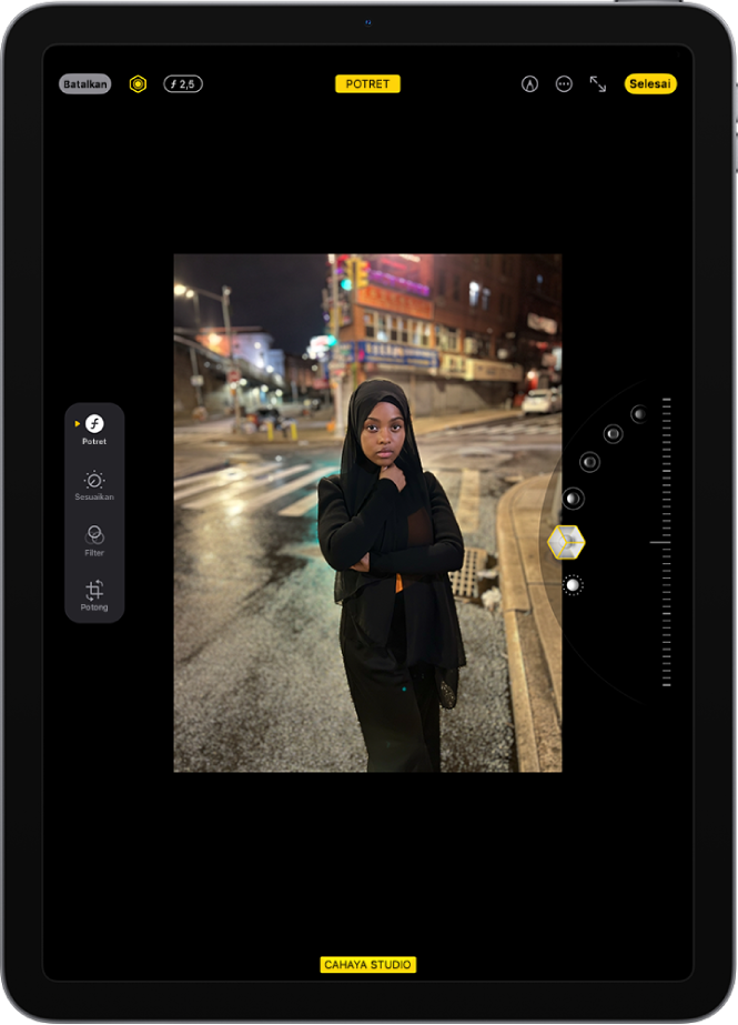 Layar Edit dari foto mode Potret. Foto berada di tengah layar dan di sisi kanan layar terdapat pilihan efek Pencahayaan Potret. Cahaya Studio dipilih dan terdapat penggeser untuk menyesuaikan level efek. Di sisi kiri layar terdapat tombol Potret, Sesuaikan, Filter, dan Potong. Tombol Potret dipilih.