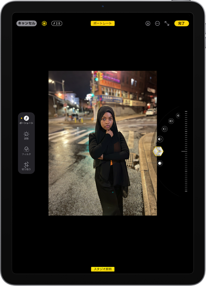 ポートレートモードの写真の「編集」画面。写真が画面の中央にあり、画面の右側にはポートレート照明エフェクトオプションが並んでいます。「スタジオ照明」ボタンが選択され、エフェクトのレベルを調整するスライダが表示されています。画面の左側には、「ポートレート」、「調整」、「フィルタ」、および「切り取り」の各ボタンがあります。「ポートレート」ボタンが選択されています。