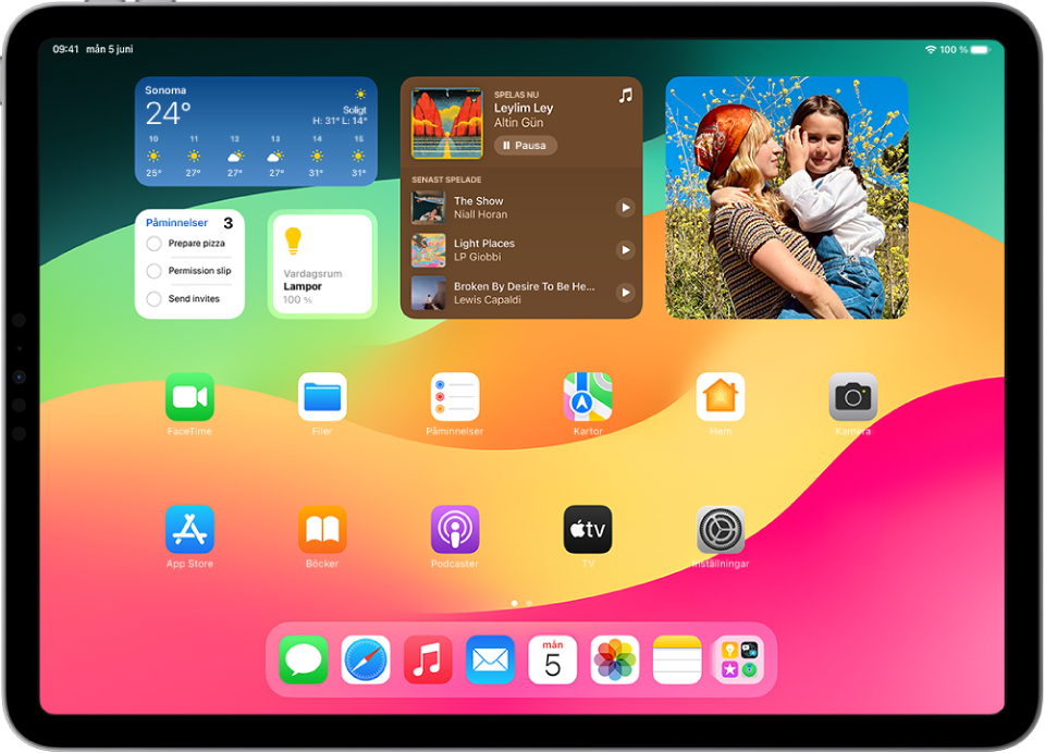 Hemskärmen på iPad. Överst på skärmen finns anpassade widgetar för följande appar: Klocka, Hitta, Väder, Bilder och Kalender.
